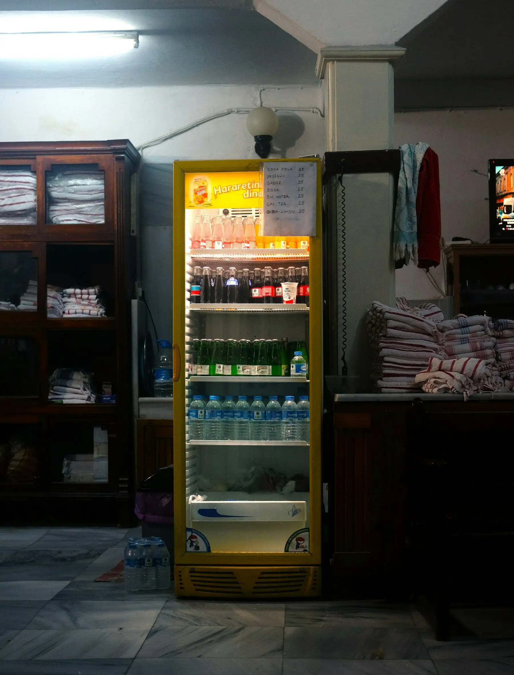 A yellow glass-door refrigerator filled with drinks